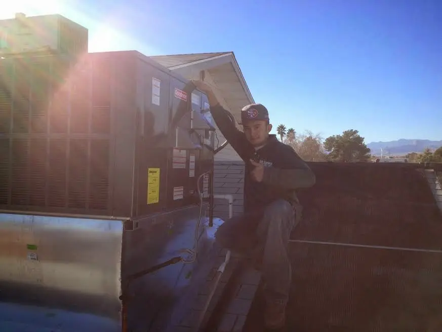 HVAC technician performing AC Tune-Up on a rooftop unit in Prosser